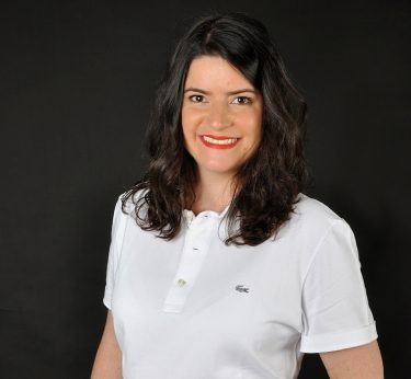 Célandine Rigoulot Femme souriante en polo blanc sur fond noir.