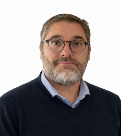 Christophe_Vitiello Homme souriant avec des lunettes et un pull, fond blanc.